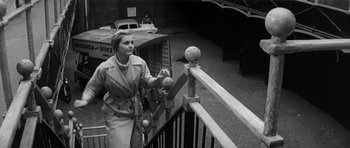 Movie still from “Bunny Lake Is Missing” (1965), directed by Otto Preminger – An old photo of a woman walking down the stairs; Medium shot, Low angle