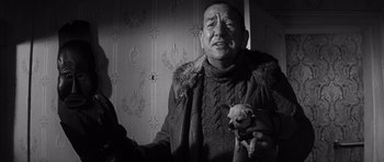 Movie still from “Bunny Lake Is Missing” (1965), directed by Otto Preminger – An older man holding a small dog in his hands; Close Up shot, Low angle