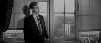 Movie still from “Bunny Lake Is Missing” (1965), directed by Otto Preminger – A black and white photo of a man in a suit looking out of a window; Medium shot, Low angle