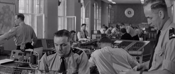 Movie still from “Bunny Lake Is Missing” (1965), directed by Otto Preminger – A black and white photo of people working on computers; Medium shot, Low angle