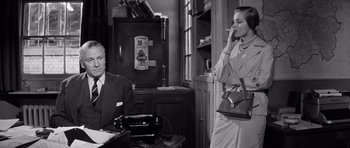 Movie still from “Bunny Lake Is Missing” (1965), directed by Otto Preminger – A man and a woman are talking to each other in an office setting; Medium shot, Low angle