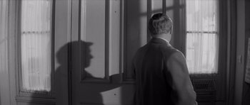 Movie still from “Bunny Lake Is Missing” (1965), directed by Otto Preminger – A man standing in front of a window with his shadow on the wall; Close Up shot, Over the shoulder angle