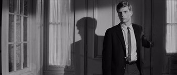 Movie still from “Bunny Lake Is Missing” (1965), directed by Otto Preminger – A black and white photo of a man standing in front of a window; Close Up shot, Low angle