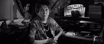 Movie still from “Bunny Lake Is Missing” (1965), directed by Otto Preminger – An older woman sitting at a table in a room; Close Up shot, Low angle