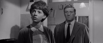 Movie still from “Bunny Lake Is Missing” (1965), directed by Otto Preminger – A man and a woman standing next to each other in a room; Medium shot, Low angle