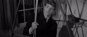 Movie still from “Bunny Lake Is Missing” (1965), directed by Otto Preminger – A black and white photo of a man holding a rope; Close Up shot, High angle