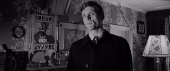 Movie still from “Bunny Lake Is Missing” (1965), directed by Otto Preminger – A black and white photo of a man in a suit and tie; Close Up shot, Low angle