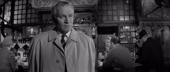 Movie still from “Bunny Lake Is Missing” (1965), directed by Otto Preminger – An older man in a trench coat and a tie; Close Up shot, Low angle