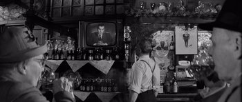 Movie still from “Bunny Lake Is Missing” (1965), directed by Otto Preminger – A man standing in front of a television in a bar; Medium shot, Over the shoulder angle