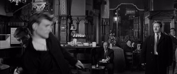 Movie still from “Bunny Lake Is Missing” (1965), directed by Otto Preminger – A man in a suit sitting in front of another man in a suit; Wide shot, Over the shoulder angle