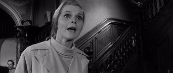 Movie still from “Bunny Lake Is Missing” (1965), directed by Otto Preminger – A black - and - white photo of a woman standing next to a staircase; Close Up shot, Low angle