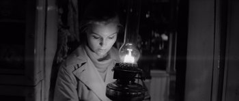 Movie still from “Bunny Lake Is Missing” (1965), directed by Otto Preminger – A woman looking at an oil lamp in a dimly - lit room; Medium shot, Low angle