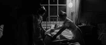 Movie still from “Bunny Lake Is Missing” (1965), directed by Otto Preminger – Three nurses in a hospital room with a patient in a bed; Medium shot, Low angle