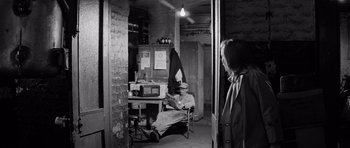 Movie still from “Bunny Lake Is Missing” (1965), directed by Otto Preminger – An older man sitting in a chair in a room; Wide shot, Over the shoulder angle