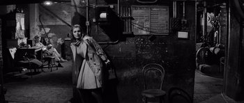 Movie still from “Bunny Lake Is Missing” (1965), directed by Otto Preminger – A black and white photo of a woman standing in front of a wall; Wide shot, High angle