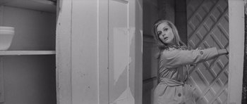 Movie still from “Bunny Lake Is Missing” (1965), directed by Otto Preminger – Black and white photograph of a woman standing in front of a door; Medium shot, Low angle