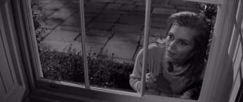 Movie still from “Bunny Lake Is Missing” (1965), directed by Otto Preminger – A woman leaning up against a window sill; Medium shot, High angle