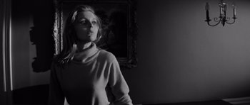 Movie still from “Bunny Lake Is Missing” (1965), directed by Otto Preminger – A black and white photo of a woman in front of a painting; Medium shot, Low angle