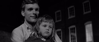 Movie still from “Bunny Lake Is Missing” (1965), directed by Otto Preminger – A man and a little girl standing next to each other in front of a building; Close Up shot, Low angle