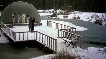 Movie still from “Burnt by the Sun” (1994), directed by Nikita Mikhalkov – A person sitting on a bench in the middle of the snow; Extreme Wide shot, High angle