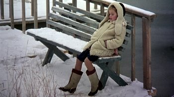 Movie still from “Burnt by the Sun” (1994), directed by Nikita Mikhalkov – A young girl sitting on a bench in the snow; Wide shot, High angle