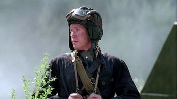 Movie still from “Burnt by the Sun” (1994), directed by Nikita Mikhalkov – A man wearing a helmet and holding a rifle; Close Up shot, Low angle