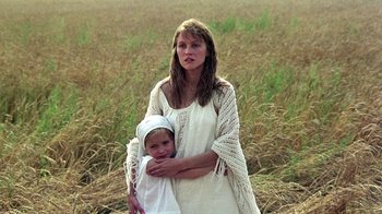 Movie still from “Burnt by the Sun” (1994), directed by Nikita Mikhalkov – A woman holding a baby in a field of tall grass; Close Up shot, Low angle