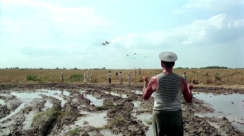 Movie still from “Burnt by the Sun” (1994), directed by Nikita Mikhalkov – A group of people standing in the mud flying kites; Wide shot, Over the shoulder angle
