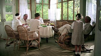 Movie still from “Burnt by the Sun” (1994), directed by Nikita Mikhalkov – A group of people sitting around a table eating food; Wide shot, High angle