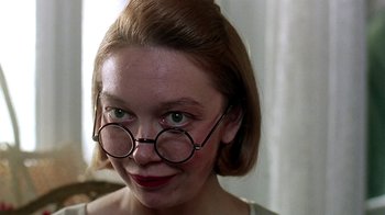 Movie still from “Burnt by the Sun” (1994), directed by Nikita Mikhalkov – A woman wearing round glasses and a short haircut; Close Up shot, Low angle