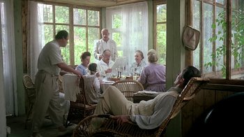 Movie still from “Burnt by the Sun” (1994), directed by Nikita Mikhalkov – A group of people sitting around a table with food; Wide shot, High angle