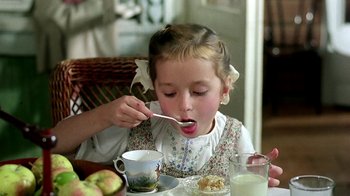 Movie still from “Burnt by the Sun” (1994), directed by Nikita Mikhalkov – A little girl is eating some food at a table; Close Up shot, High angle