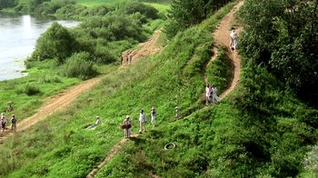 Movie still from “Burnt by the Sun” (1994), directed by Nikita Mikhalkov – A group of people walking up a hill on a dirt road; Extreme Wide shot, High angle
