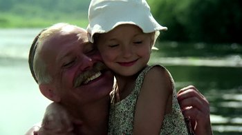 Movie still from “Burnt by the Sun” (1994), directed by Nikita Mikhalkov – An older man and a young girl smiling for the camera; Close Up shot, Low angle