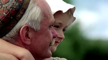 Movie still from “Burnt by the Sun” (1994), directed by Nikita Mikhalkov – An older man and a young girl are smiling together; Close Up shot, Low angle