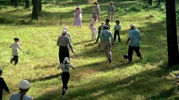 Movie still from “Burnt by the Sun” (1994), directed by Nikita Mikhalkov – A group of people walking through a grassy field; Wide shot, High angle