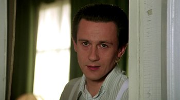 Movie still from “Burnt by the Sun” (1994), directed by Nikita Mikhalkov – A young man standing in front of a wall; Close Up shot, Low angle