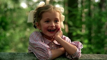 Movie still from “Burnt by the Sun” (1994), directed by Nikita Mikhalkov – A little girl sitting on top of a wooden railing; Close Up shot, Low angle