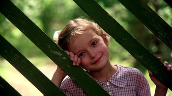 Movie still from “Burnt by the Sun” (1994), directed by Nikita Mikhalkov – A little girl leaning against a green fence; Close Up shot, Low angle