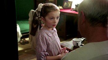 Movie still from “Burnt by the Sun” (1994), directed by Nikita Mikhalkov – A little girl is sitting at a table with an older man; Close Up shot, Over the shoulder angle