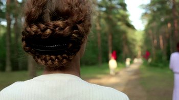 Movie still from “Burnt by the Sun” (1994), directed by Nikita Mikhalkov – A person's hair in a bun; Close Up shot, Over the shoulder angle