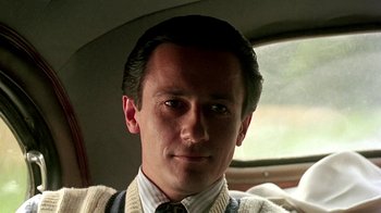 Movie still from “Burnt by the Sun” (1994), directed by Nikita Mikhalkov – A person in a car wearing a sweater; Close Up shot, Low angle