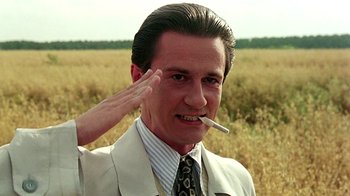 Movie still from “Burnt by the Sun” (1994), directed by Nikita Mikhalkov – A man in a suit smoking a cigarette while saluting; Close Up shot, Low angle