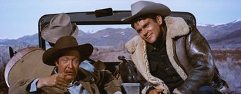 Movie still from “Bus Stop” (1956), directed by Joshua Logan – A man in a cowboy hat sitting next to another man in a cowboy hat; Medium shot, Low angle