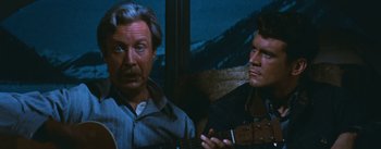 Movie still from “Bus Stop” (1956), directed by Joshua Logan – Two men sitting next to each other holding a guitar; Close Up shot, Over the shoulder angle