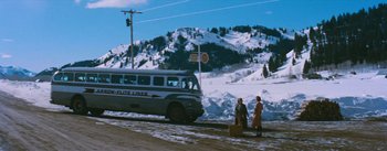 Movie still from “Bus Stop” (1956), directed by Joshua Logan – Two people standing on the side of a road near a bus; Extreme Wide shot, Low angle