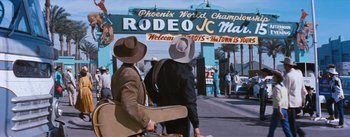 Movie still from “Bus Stop” (1956), directed by Joshua Logan – Two men wearing hats and carrying luggage walk down the street; Wide shot, Over the shoulder angle