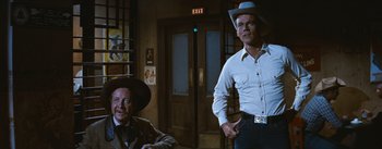 Movie still from “Bus Stop” (1956), directed by Joshua Logan – A man in a cowboy hat standing next to another man in a suit; Medium shot, Over the shoulder angle