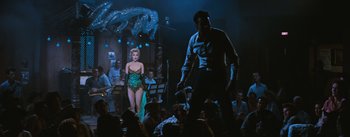 Movie still from “Bus Stop” (1956), directed by Joshua Logan – A woman in a green dress standing in front of a man; Wide shot, Low angle