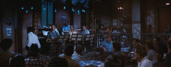 Movie still from “Bus Stop” (1956), directed by Joshua Logan – A group of people sitting around a room; Wide shot, High angle